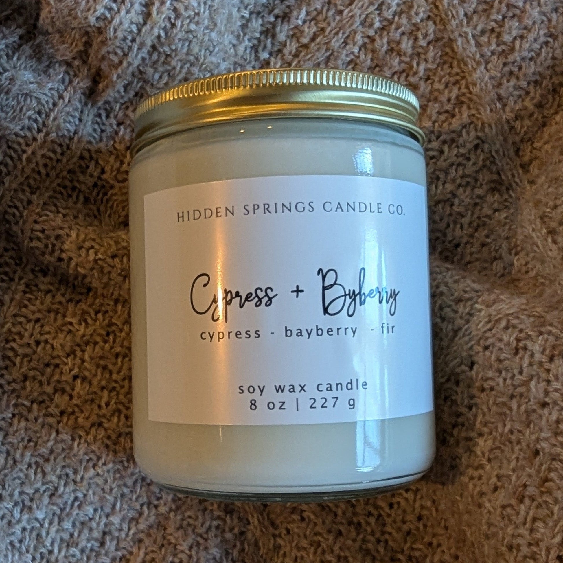 Candle jar with a label on a textured brown surface