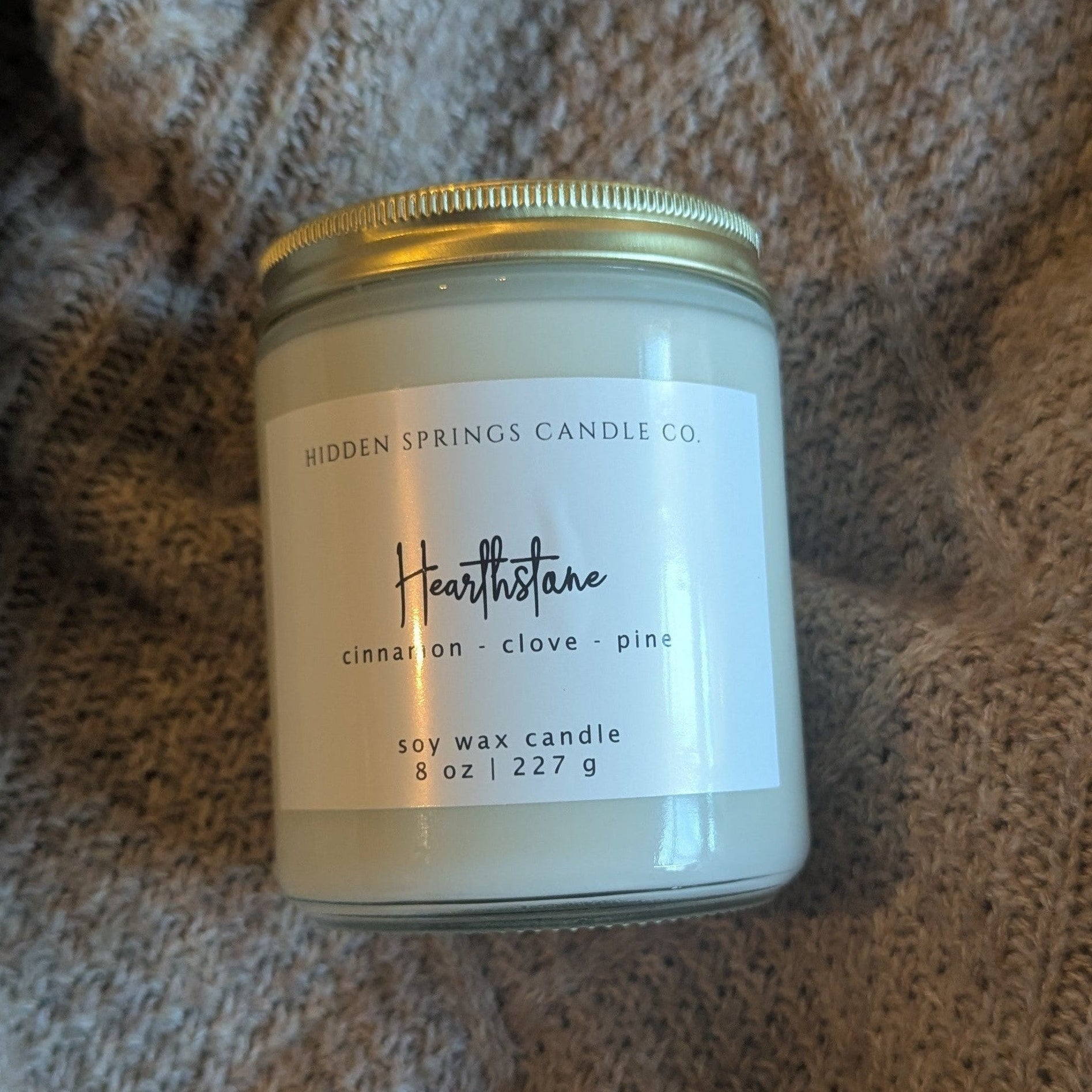 Candle jar with a label on a textured fabric background