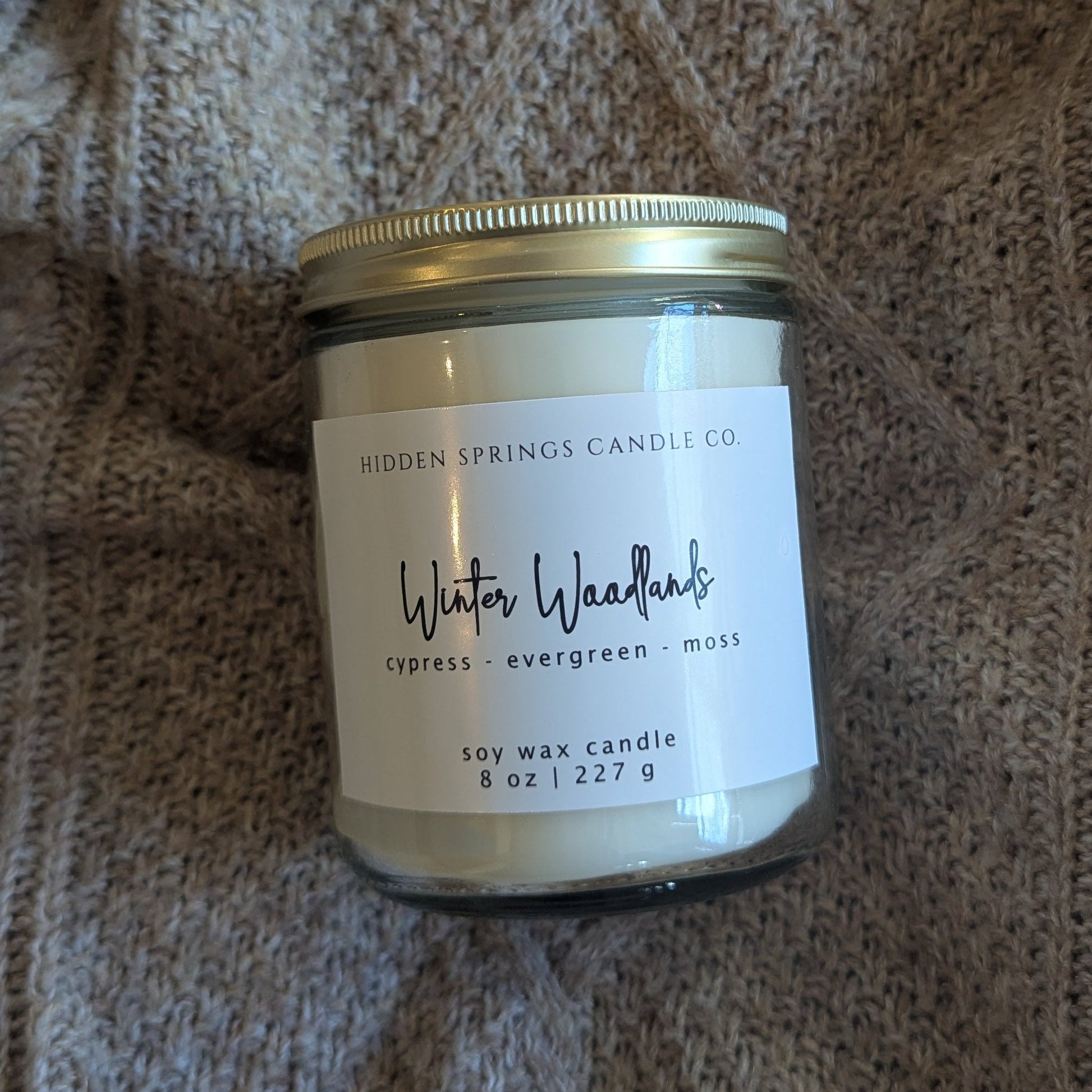 Candle jar with a label on a textured fabric background
